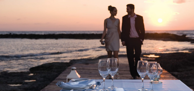 Couple making its way to dinner with a sunset over sea backdrop at one of the best all-inclusive hotels in Cyprus by Constantinou Bros