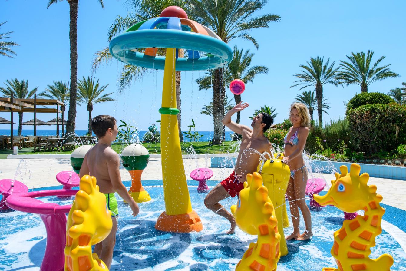 Family playing at the Oasis Splash waterpark of Constantinou Bros Athena Beach Hotel, one of the top things to do in Paphos with kids.